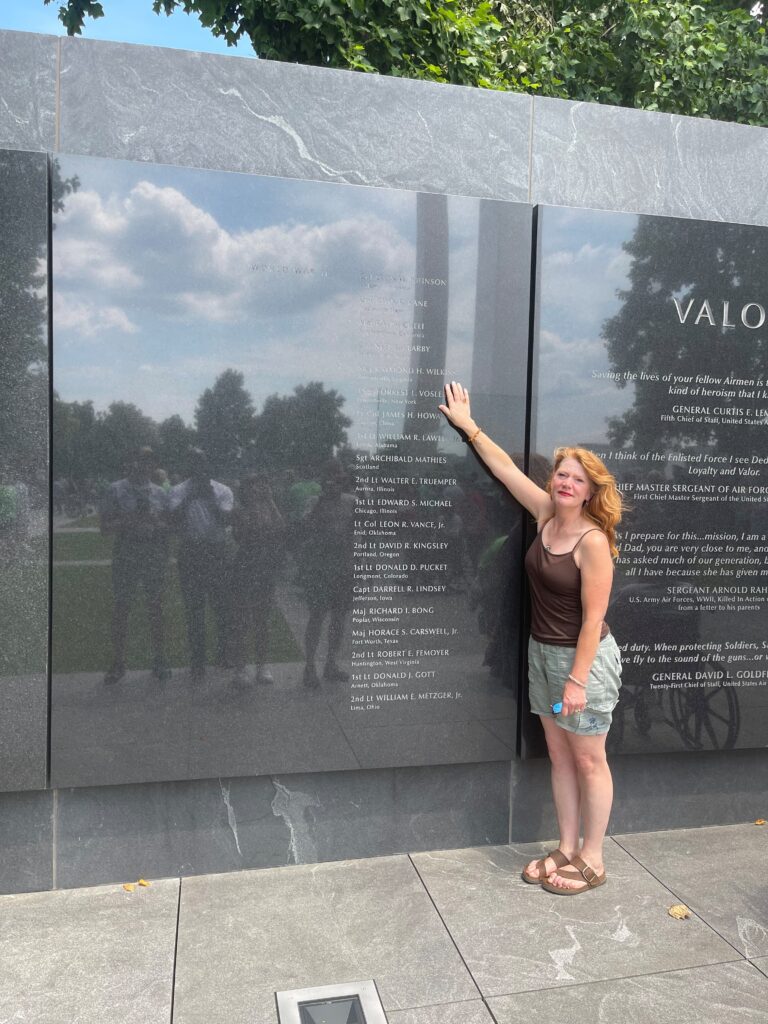 A woman standing in front of a memorial wall.